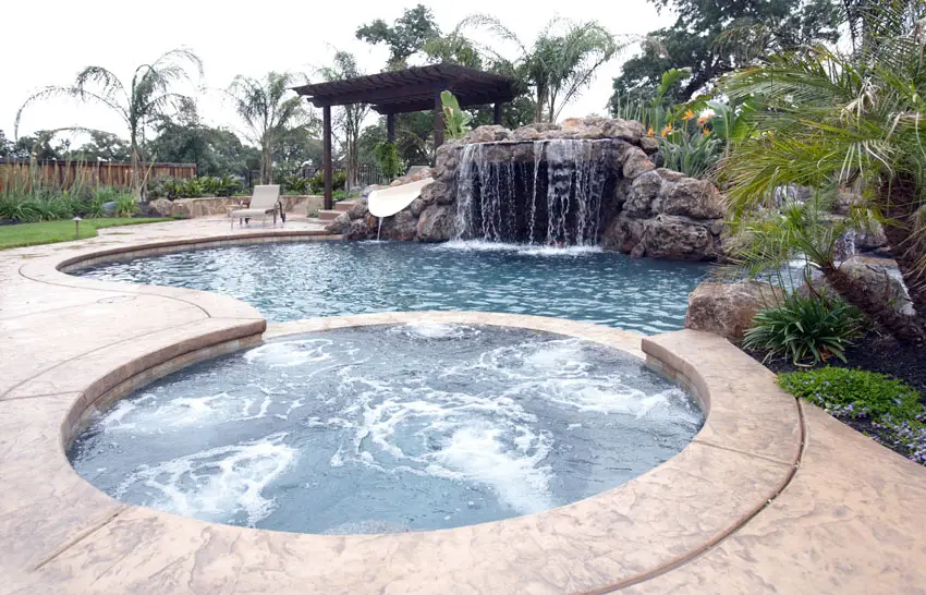 Swimming pool with rock waterfall and large hot tub