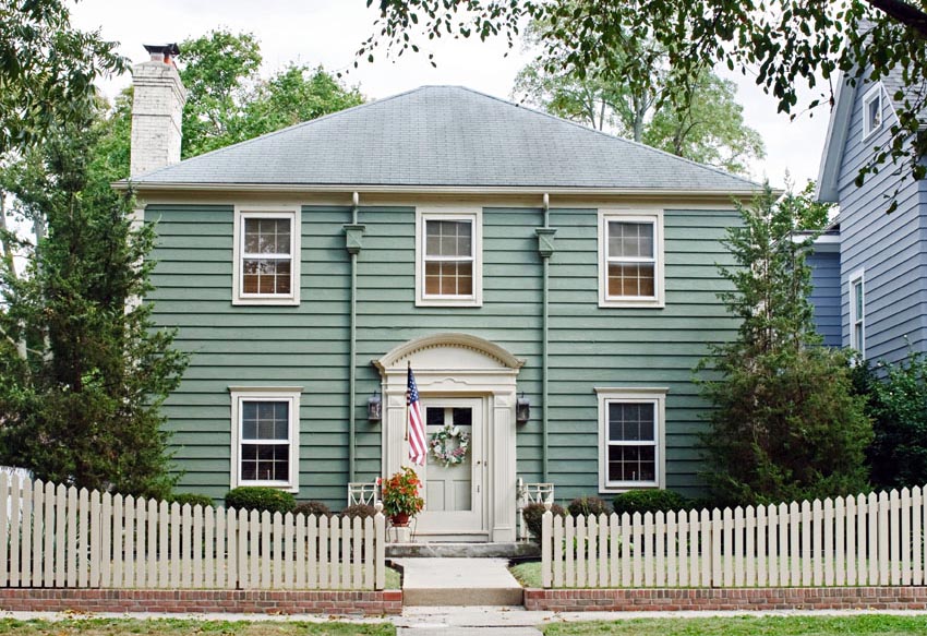 Teal house with white door and white picket fence