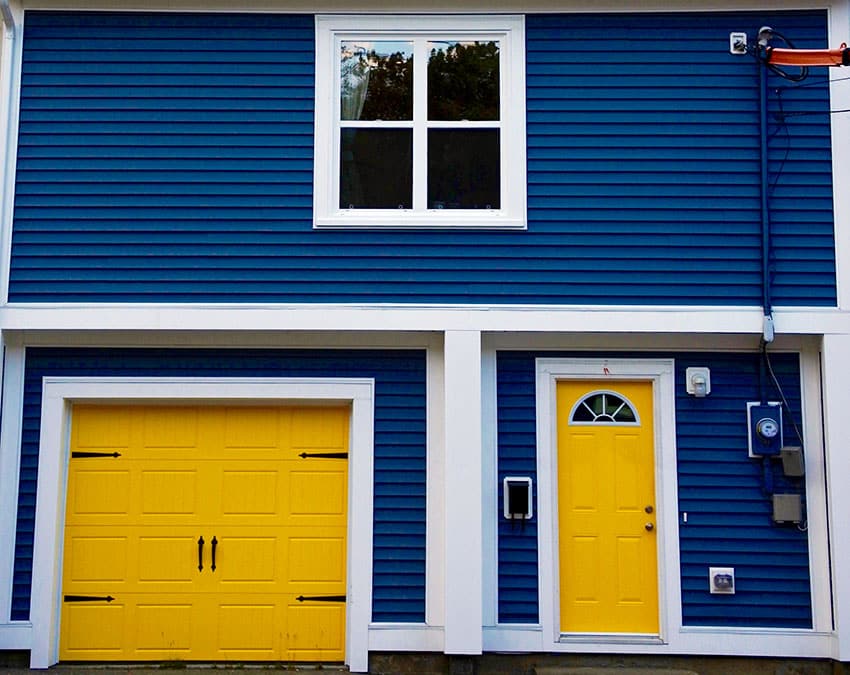 Yellow carriage style door and marine blue hued house siding