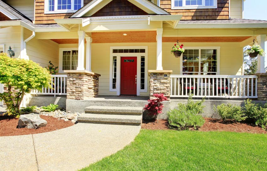 Red porch door, white columns and stone siding
