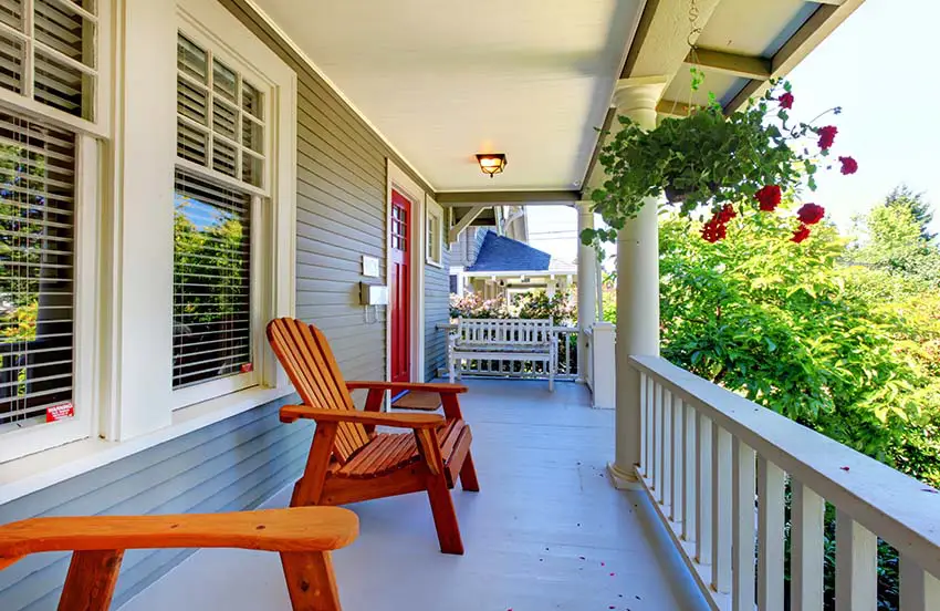 Front porch of a house with outdoor wood chairs and hanging flowers