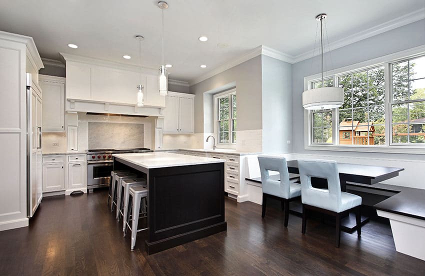 Kitchen with contrasting white main cabinets versus black island with white marble countertop
