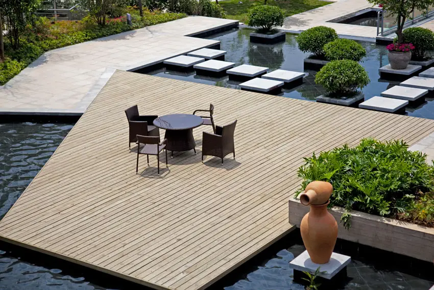 Large wood modern deck above backyard water feature pond