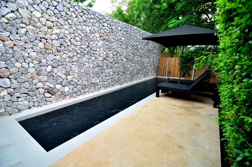 Modern rectangular pool and private villa with rock privacy wall