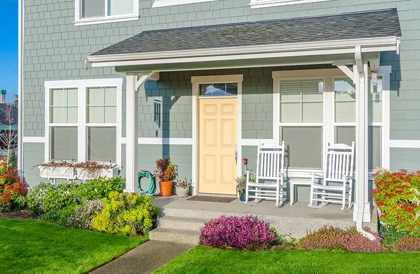 Small front porch on gray home with yellow door