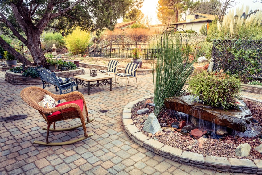 Wicker rocking chair, metal bench, trees and paver patio