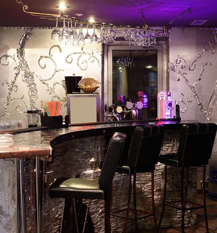 Glam home bar with curved tile countertop and black leather barstools