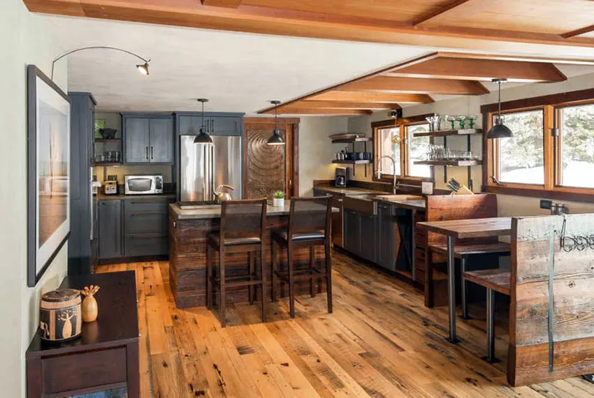 Log cabin home kitchen with gray cabinets, custom wood island, wood dining nook and wood beams