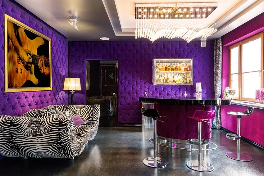 Purple home bar with chrome bar stools tufted accent wall and striped couch