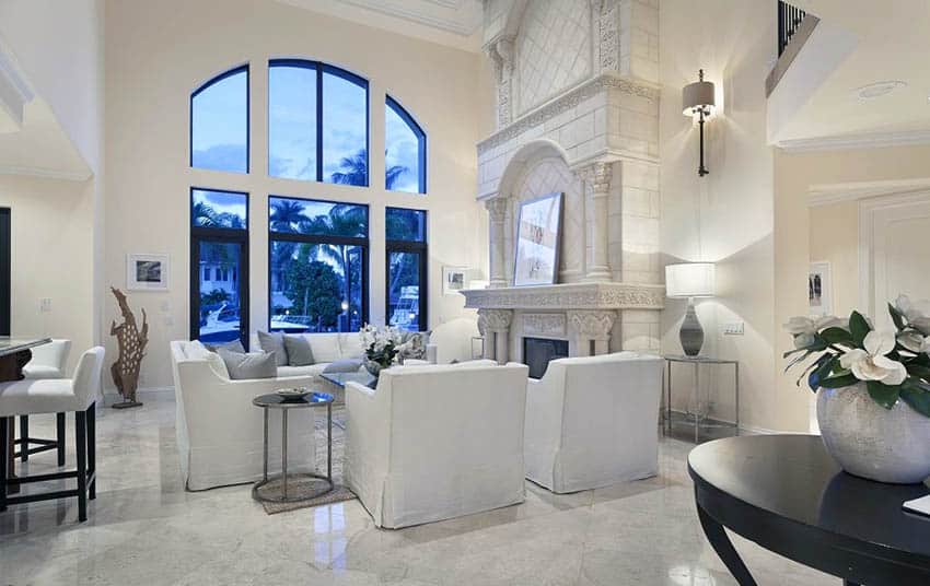 White living room with high ceilings and white furniture with arches window views