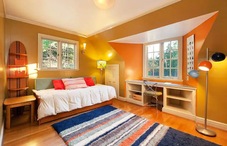 Bedroom design with orange accent wall built in desk and daybed
