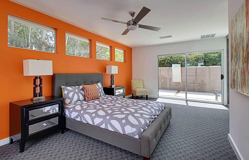 Contemporary bedroom with orange wall and gray carpet