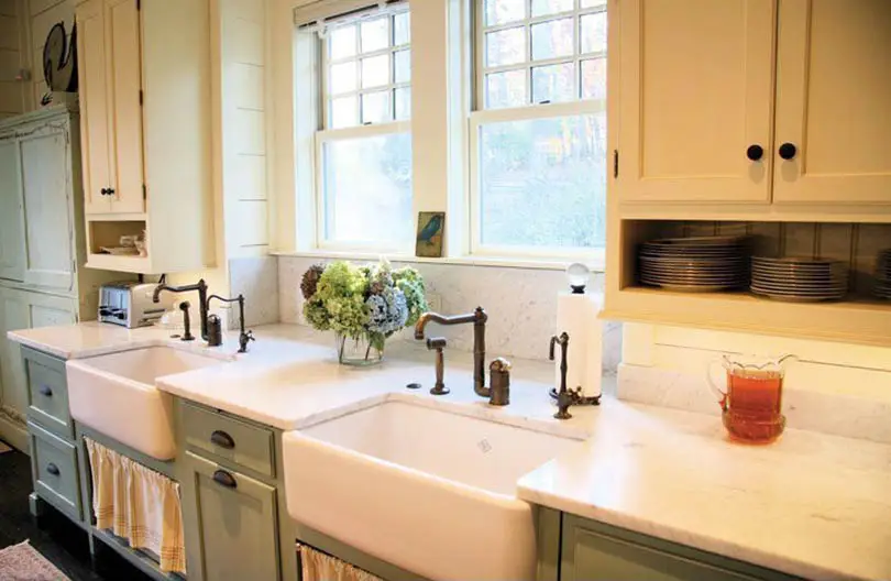 Kitchen with farmhouse sink, faucet in brass finish and stacked plates