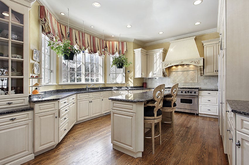 French country kitchen with white cabinets yellow painted walls and wood flooring
