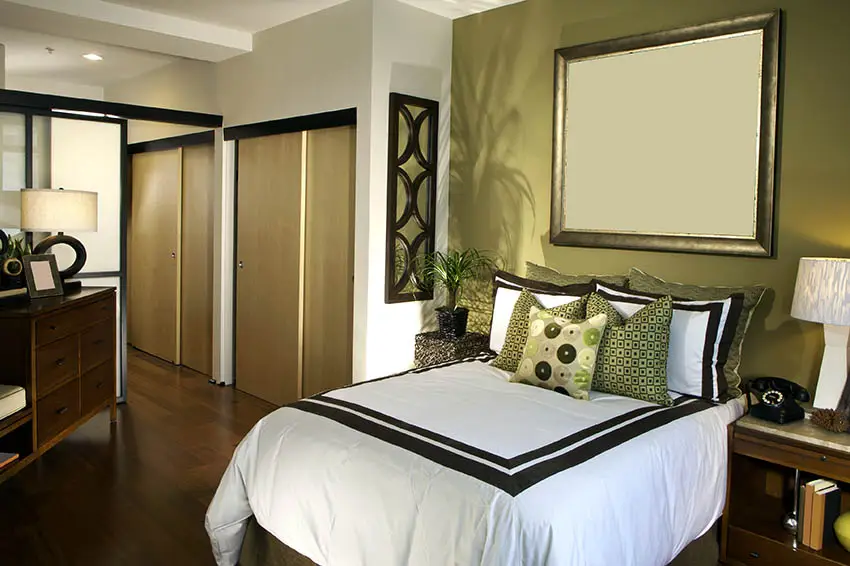 Walls in olive green shade, dark wood floors and green accent pillows