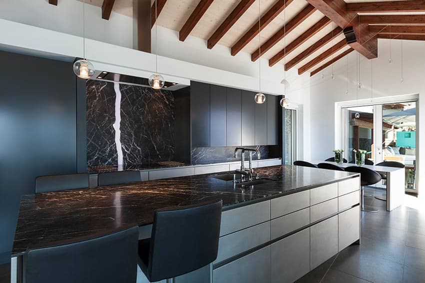 Modern kitchen with black marble accent wall and white cabinets and black marble countertop island