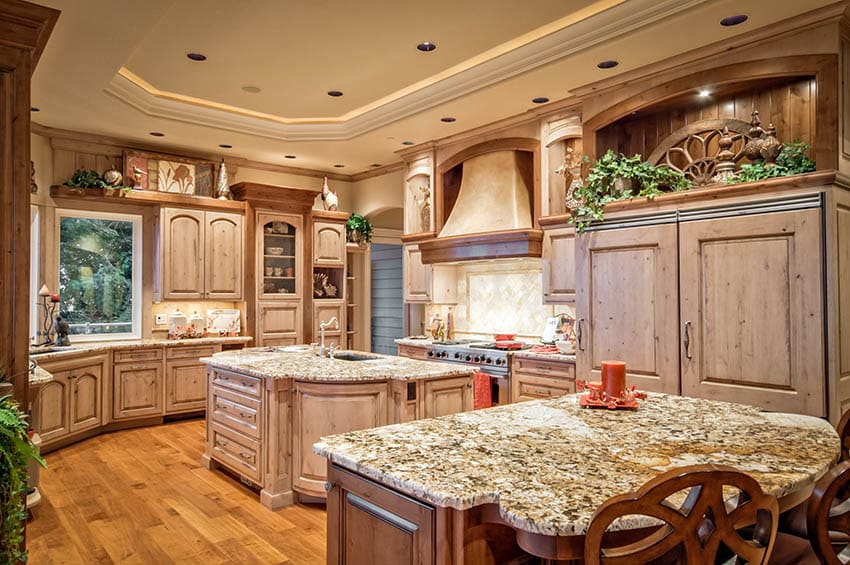 Rustic kitchen with knotty wood cabinets, custom oven hood beige granite and two islands