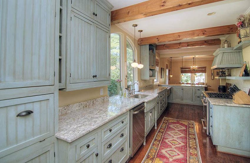 Rustic kitchen with light green weathered cabinets wood floors and exposed beams