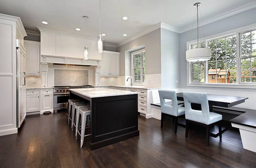 Traditional kitchen with white shaker cabinets and dark wood island with white marble counters