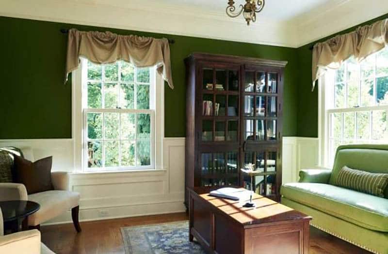Traditional living room with white wainscoting and dark green paint
