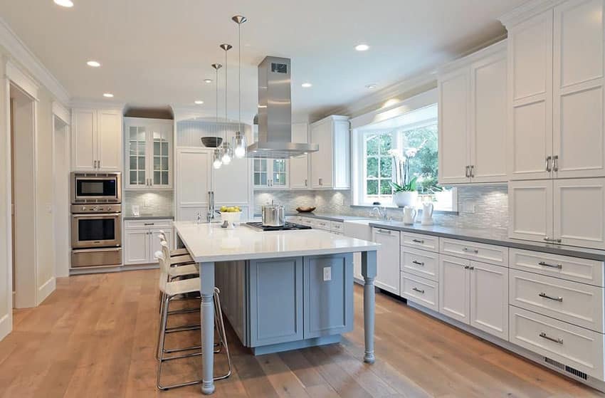 Large l shaped kitchen with white cabinets, ray island with columns and white and gray quartz countertops