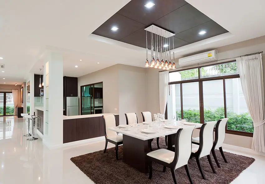 Modern dining room with recessed lights tray ceiling and linear chandelier