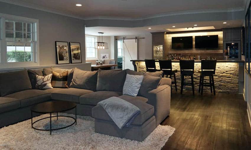 Room with wet stacked stone bar with wood backsplash under counter lights and bar stools