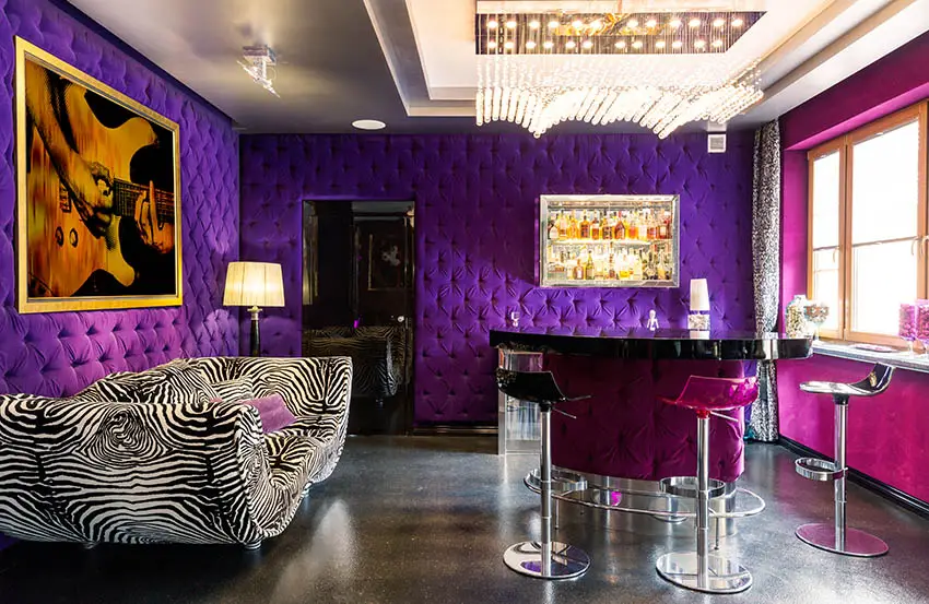 Posh basement room with tufted purple walls zebra couch and modern tufted bar