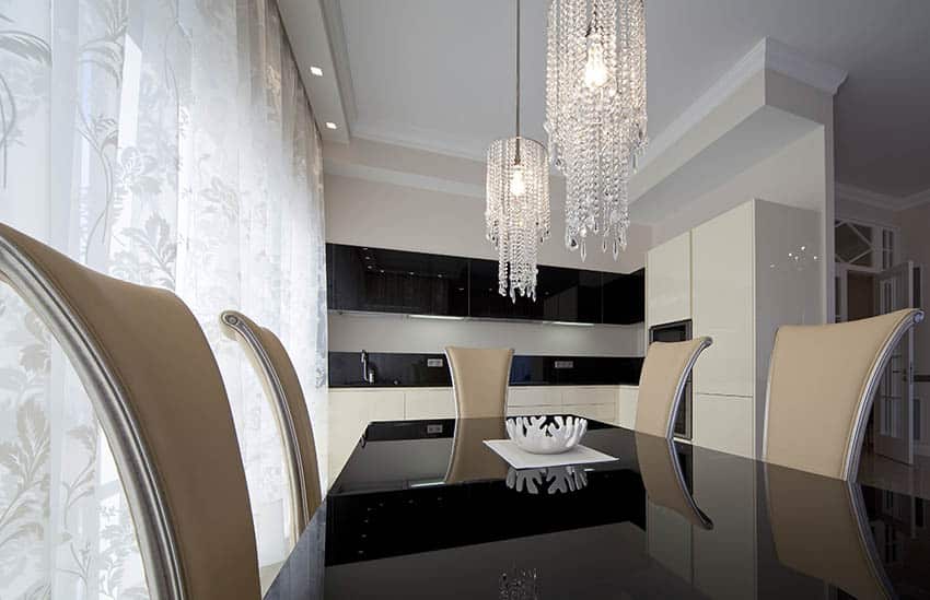 Modern dining room with two small hanging crystal chandeliers and black and white color palette