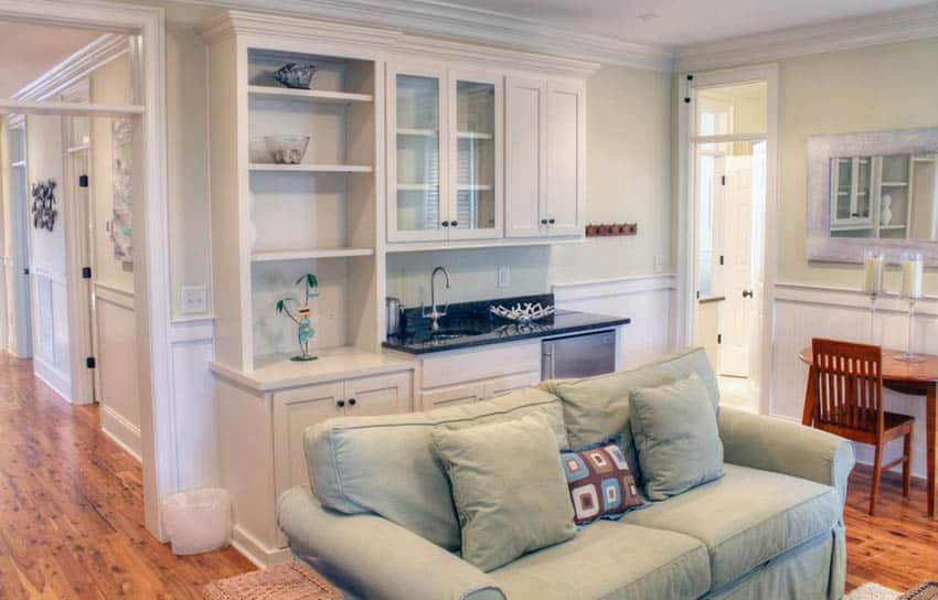 Traditional space with built in wet bar with white cupboard, sink and refrigerator