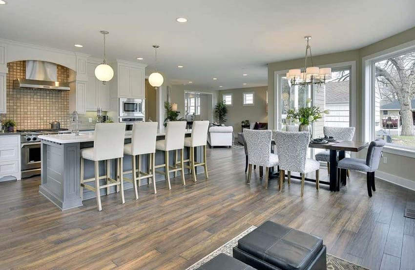 Bright kitchen with muted green walls and dining chairs and table by picture windows