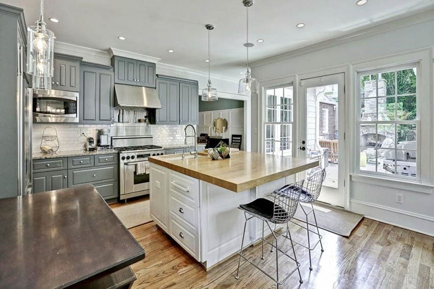 Contrasting kitchen with gray cabinets and white island with butcher block countertop