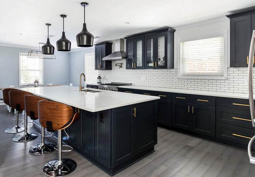 Kitchen with black cabinets, white quartz overhang countertop and wood style porcelain tile floor