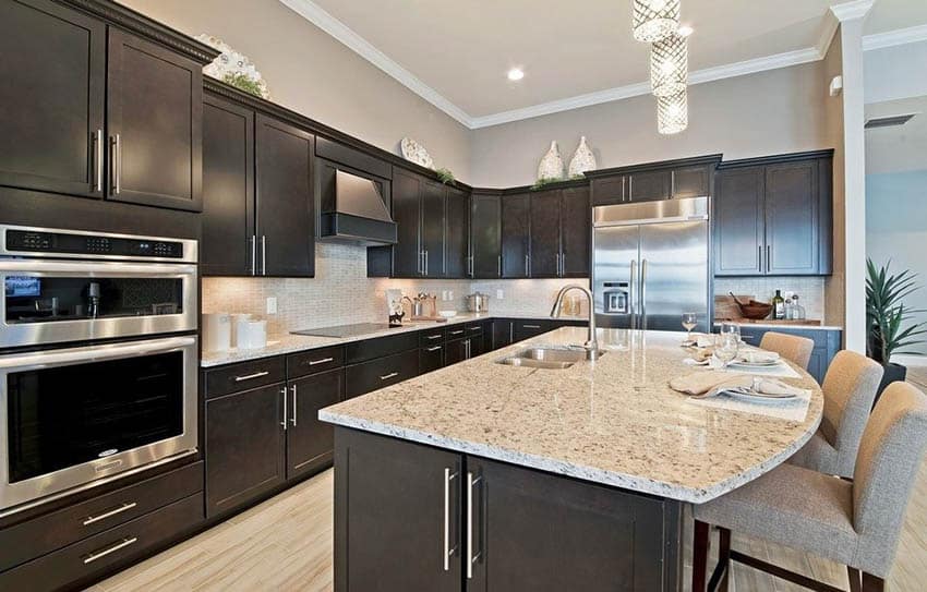 Kitchen with dark cabinets and light gray paint color walls with beige granite counters