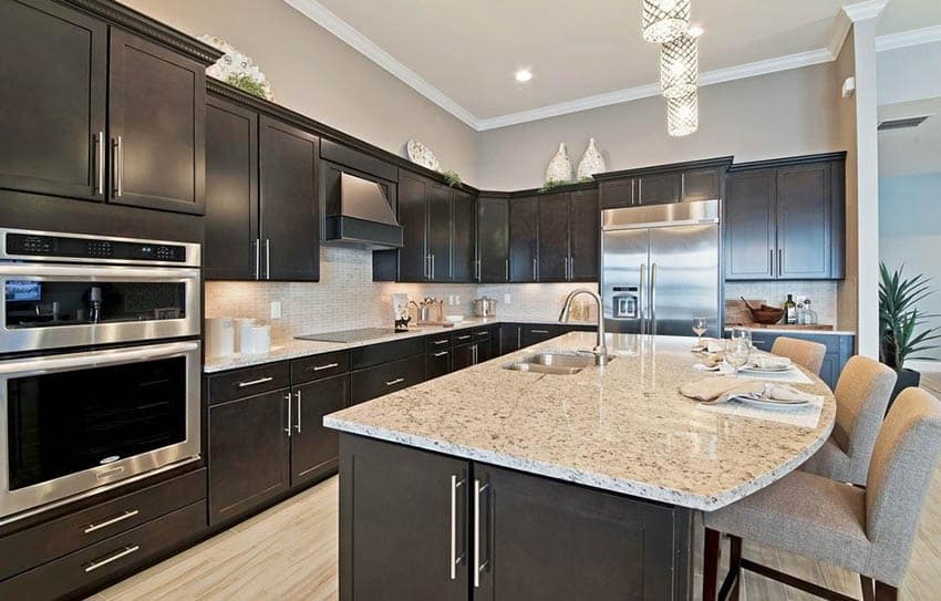 Kitchen with moldings, fabric chairs and island with sink and faucet