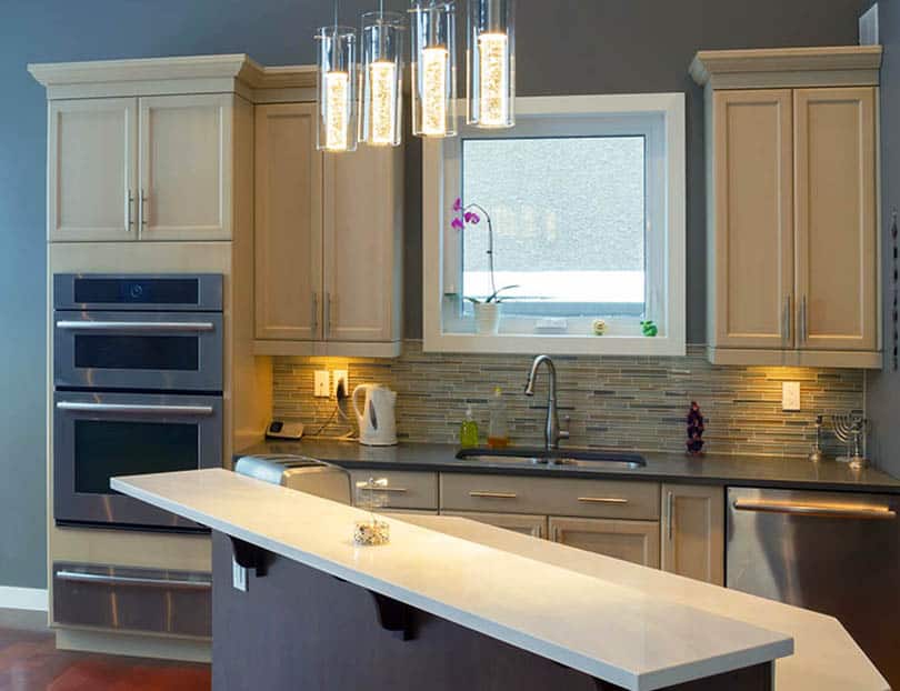 Kitchen with light wood cabinets and dark blue painted walls with island and white solid surface countertop