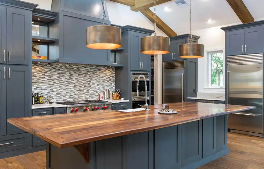 Kitchen with navy colored cabinets, mosaic backsplash and drum type lights