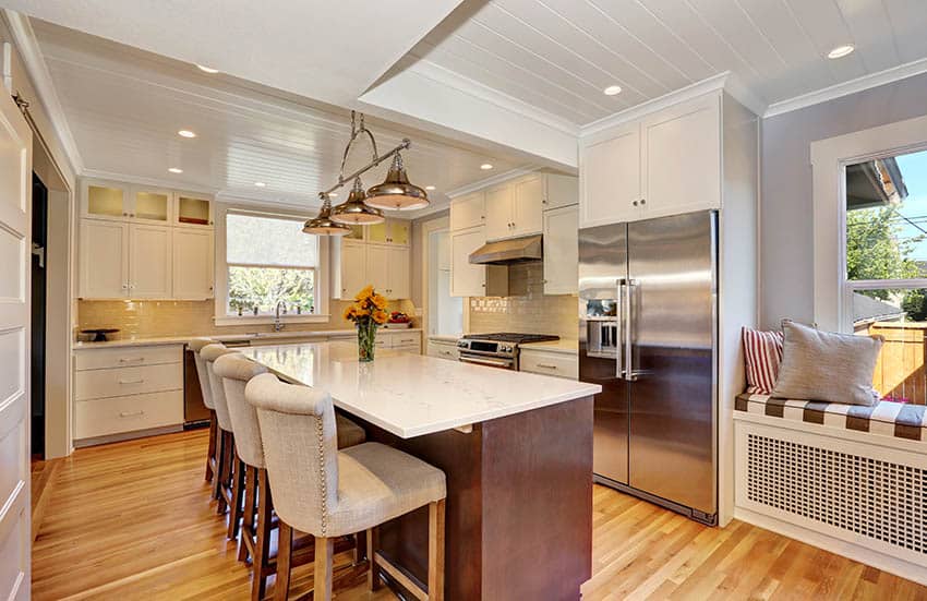 Kitchen with white painted plank ceiling and light gray walls with white cabinets and window seat