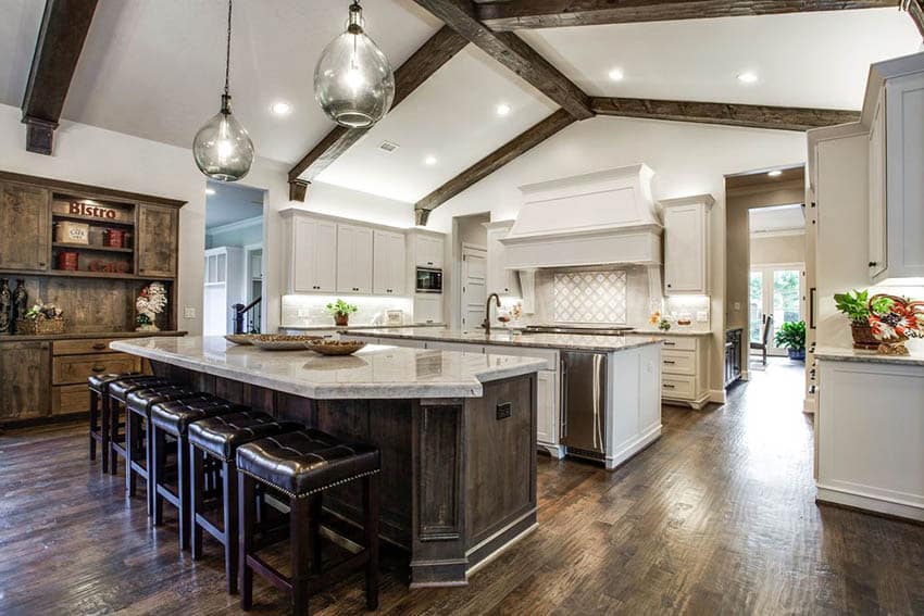 Open concept kitchen with two islands, white shaker cabinets and dark wood flooring