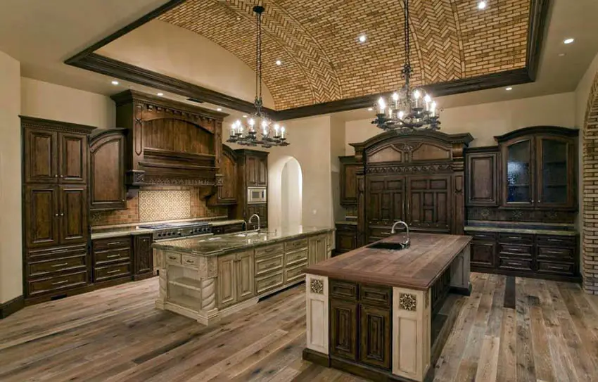 Kitchen with mosaic ceiling, cabinets in heavy wood finish and two chandeliers