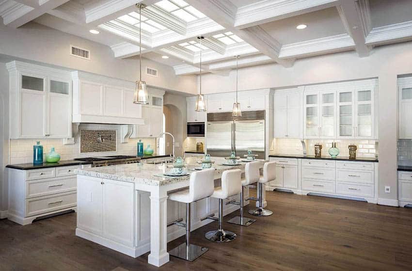 Open concept kitchen with white cabinets, large island with marble countertops and wood flooring