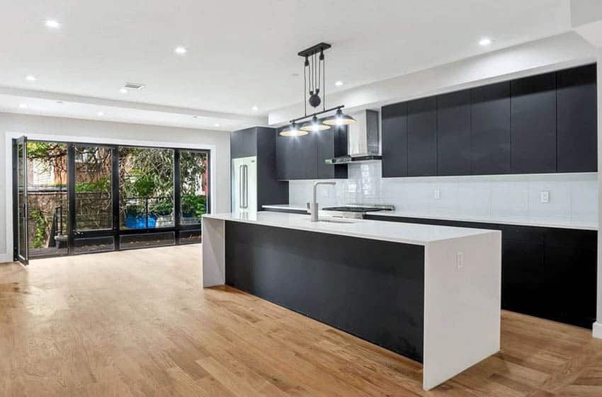 Streamlined kitchen with ink black matte cabinets and white waterfall quartz 