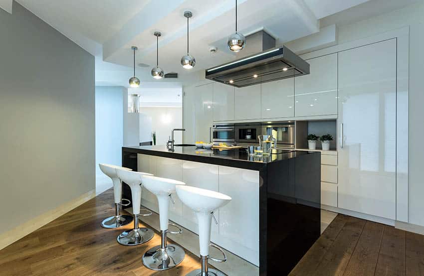 Modern kitchen with white high gloss cabinets and gray painted wall with black counters and dark wood flooring