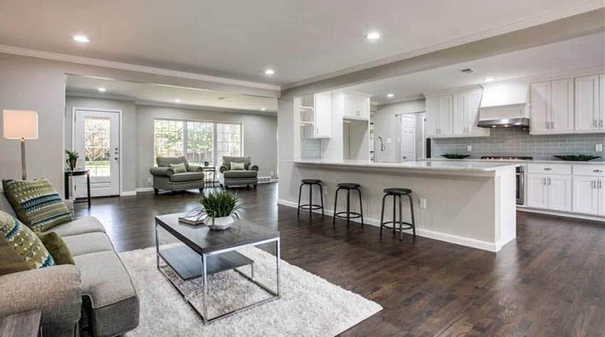 Open plan kitchen with peninsula, white cabinets, wood floors and tile backsplash