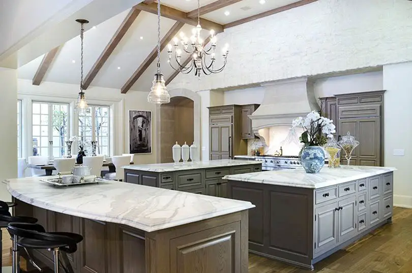 Kitchen with three islands, marble countertops, chandelier, dining nook and wood flooring