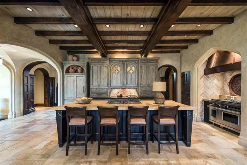Large gothic style kitchen design with travertine flooring, dark wood cabinets, exposed beam ceiling and arched walls