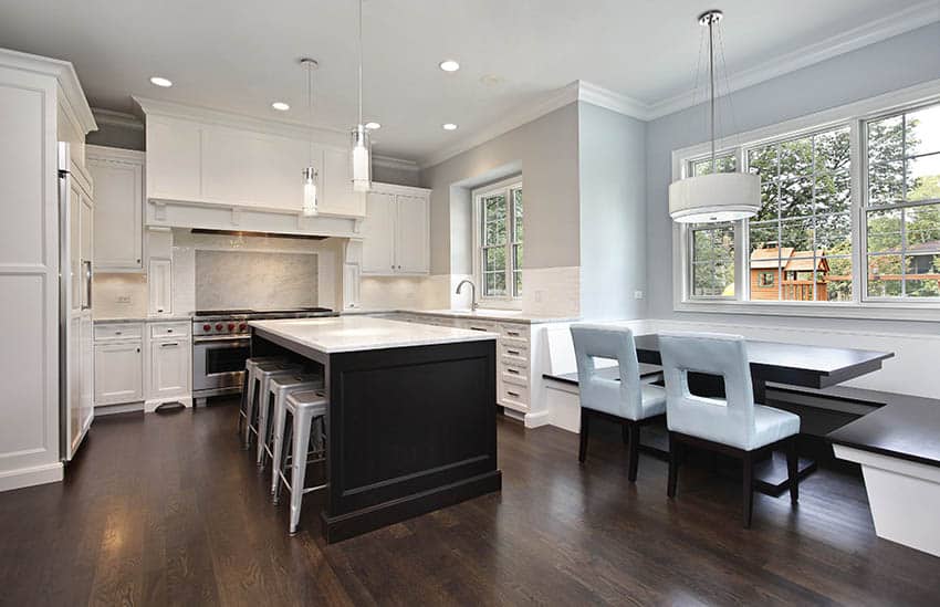 Transitional kitchen with white cabinets, light gray painted walls, dark wood island and marble counters