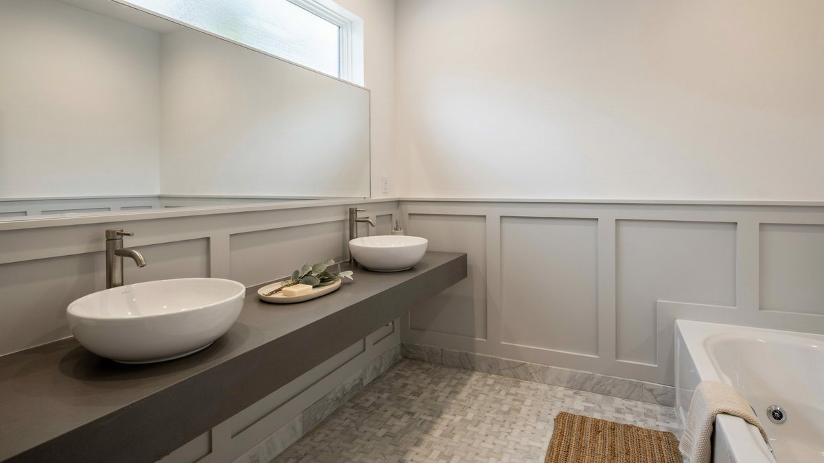 Gray master bath with wainscoting, dual sinks, and basket-weave marble tile