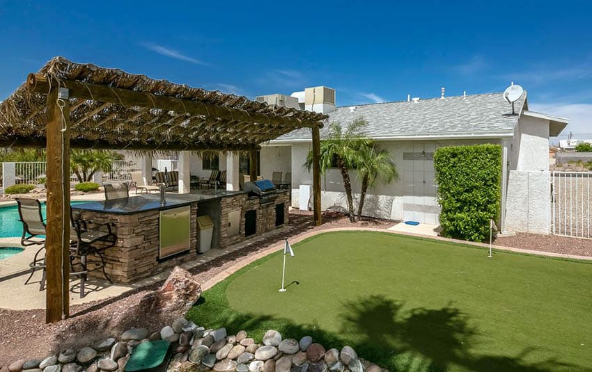 Backyard putting green with pool outdoor kitchen and wood pergola