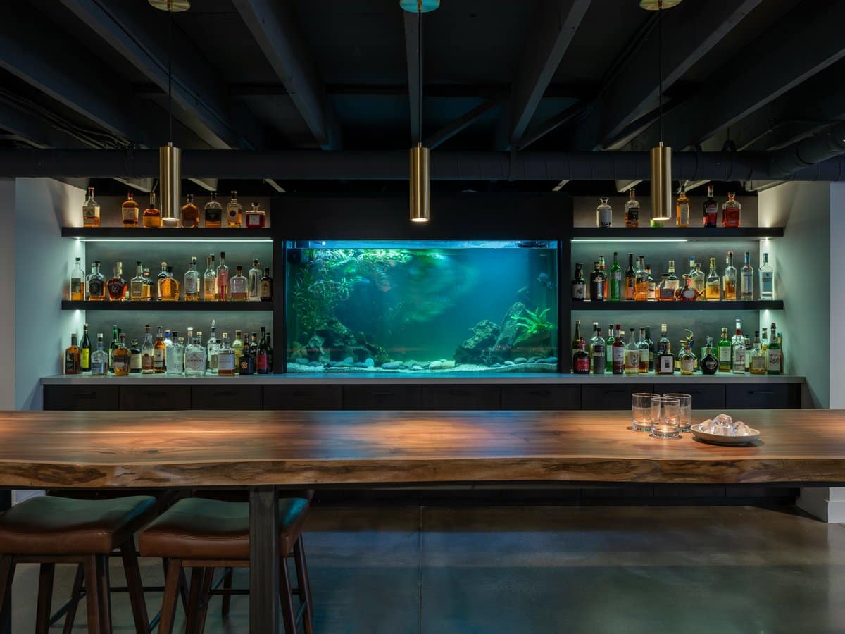 Live edge wood bar counter backed by a glowing built in aquarium wall